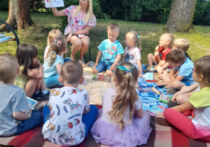 Pani Małgosia czyta dzieciom z grupy III książkę w ogrodzie