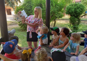 Pani Małgosia czyta dzieciom z grupy II książkę w ogrodzie