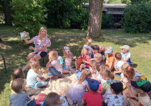 Pani Małgosia czyta dzieciom książkę w ogrodzie