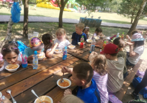 Dzieci przy stole jedzą obiad