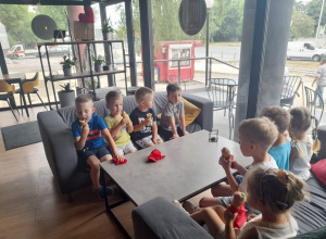 Dzieci siedzą na kanapach i jedzą lody