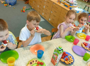 Kilkoro dzieci przy stole jedzą gofry