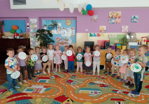 Dzieci z grupy Biedronki stoją w półkolu z pracą plastyczną- piłka w kropki