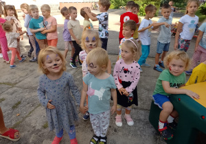 Kilkoro dzieci z grupy Biedronki stoją z pomalowanymi buziami