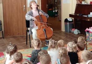 Dzieci słuchają, jak gość gra na wiolonczeli