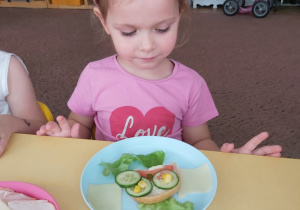 Dziewczynka patrzy na kanapkę na talerzyku