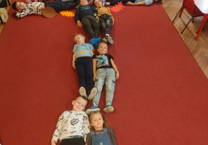 Dzieci leżą na dywanie tworząc drzewo
