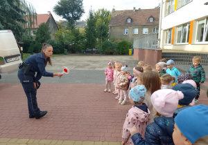 Pani policjantka pokazuje dzieciom lizaka policyjnego