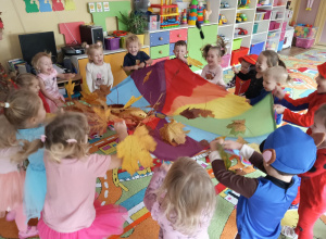 Dzieci podczas zabawy z chusta i liśćmi