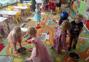 Dzieci noszą orzeszki i kasztanki do misek