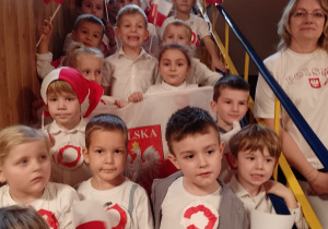 Dzieci stoją w holu przedszkola i śpiewają hymn