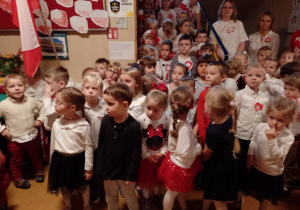 Dzieci stoją w holu przedszkola i śpiewają hymn