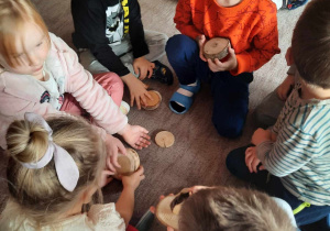 Kilkoro dzieci na dywanie segreguje plastry drewna