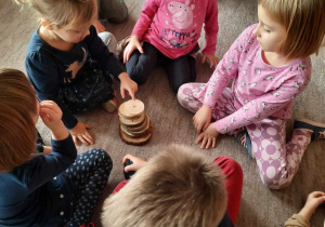Kilkoro dzieci układa wieżę z plastrów drewna