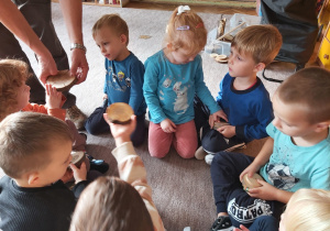 Dzieci siedzą na dywanie i dotykają plastry drewna