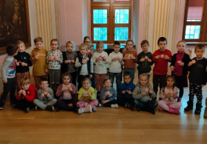 Grupowe zdjęcie dzieci z kotylionami w muzeum