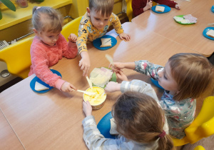 Kilkoro dzieci smaruje masłem pieczywo
