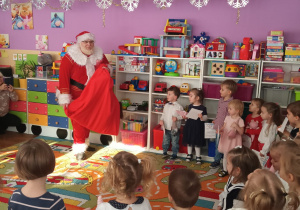 Mikołaj pokazuje dzieciom worek z prezentem
