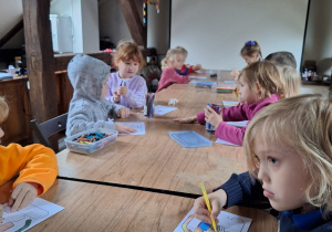 Dzieci podczas wykonywania pracy plastycznej prz stolikach
