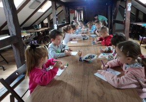 Dzieci przy stole kolorują szablon ozdoby świątecznej