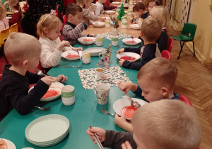 Dzieci z grupy Ważki i inne z paniami siedzą przy wigilijnym obiedzie