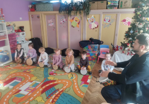 Siedmioro dzieci z grupy Biedronki i gość grają na bębnach