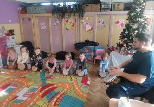 Siedmioro dzieci z grupy Biedronki i Ważki z gościem grają na bębnach