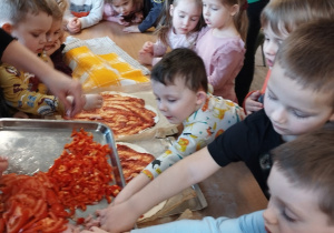 Dzieci posypują pizze dodatkami