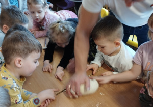 Pan Tomasz pokazuje dzieciom, jak zagniata się ciasto na pizzę