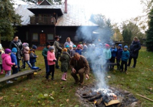 Dzieci podają leśniczemu ziemniaki do ogniska