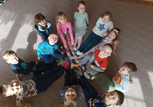 Dzieci z grupy Pszczółki siedzą na dywanie pokazując swoje skarpetki