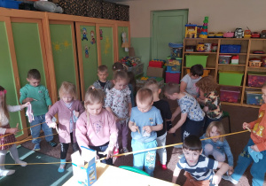 Dzieci z grupy Ważki wieszają na sznurku skarpetki za pomocą klamerek