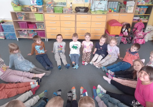 Dzieci z grupy Biedronki siedzą i pokazuja swoje skarpetki