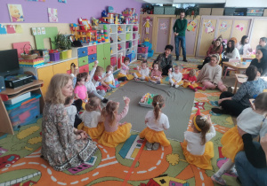 Pani Sylwia, pani Ewa z dziećmi siedzą na dywanie i pokazują pisanki