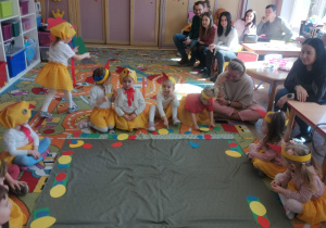 Dzieci siedząc na dywanie układają na kartonikach sylwety pisanek