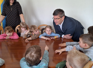 Dzieci siedzą przy stole i rozmawiają z Panem Prezydentem
