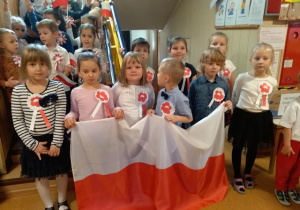 Na pierwszym planie dzieci z grupy V z flagą Polski