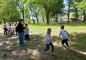 Dzieci kolejno nakładają papierowe tytki na sznurek