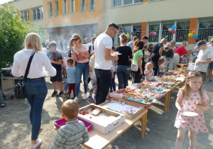 Rodzice i dzieci przy stolikach ze słodkościami