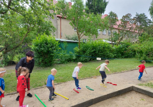 dzieci przeskakuja przez drążki i szarfy