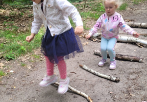 Maja i Laura z grupy Biedronki skacząprzez ułożone patyki