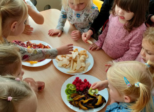 Dzieci przy stoliku jedzą owoce