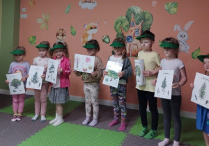 Kilkoro dzieci stoi i trzyma w rękach obrazki z sylwetami drzew