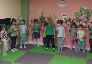 Grupa dzieci tzryma i macha zielonymi gałązkami