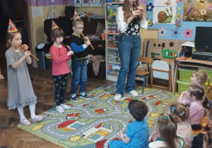 Troje dzieci i pani muzyk grają na flecie