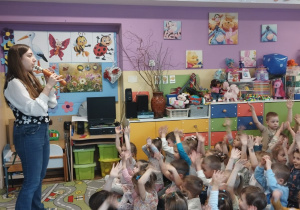 Pani muzyk gra na "marchewce", a dzieci siedzą i słuchają