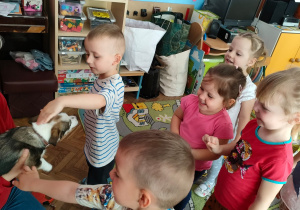 Pani Ania trzyma na rękach pieska, a chłopiec go głaszcze