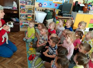 Pani Ania siedzi z pieskiem przed dziećmi