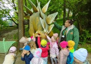 Pani przewodnik i dzieci dotykają dinozaura