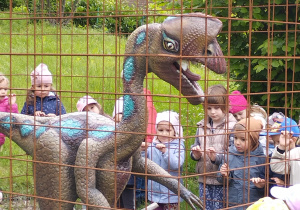 Dzieci przy dinozaurze w klatce